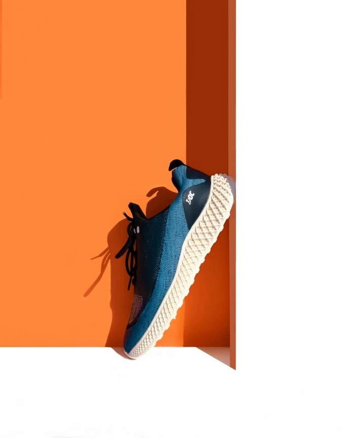 a pair of blue sneakers sitting on top of an orange wall